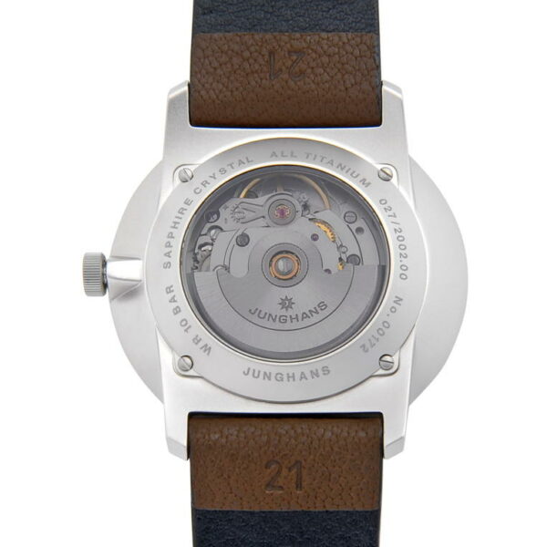 Das Bild zeigt die Rückseite der mechanischen Armbanduhr Junghans FORM A Titan mit transparentem Gehäuse, das ihr Innenleben zeigt. Sie verfügt über ein Titangehäuse und ein zweifarbiges Lederarmband in Braun und Schwarz mit verschiedenen Inschriften am Gehäuserand.