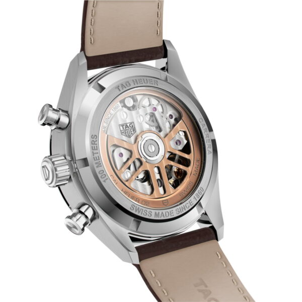 Das Bild zeigt die Rückseite einer TAG Heuer-Uhr mit transparentem Gehäuse, das das komplexe mechanische Uhrwerk im Inneren offenbart. Das Gehäuse ist silberfarben mit einem beigefarbenen Lederarmband und am Rand ist „100 METERS SWISS MADE“ eingraviert.