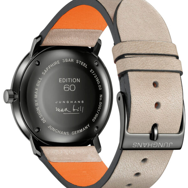 Rückseite der Armbanduhr Junghans Max Bill Regulator Edition 60 mit beigem Lederarmband mit orangefarbenem Innenfutter, schwarzem Gehäuse und Editionstext; Design von Max Bill mit Angaben wie „3 BAR“ und „EDELSTAHL“.