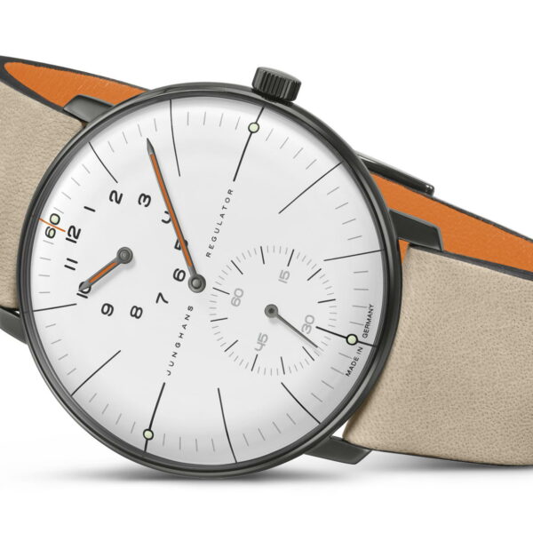 Die Armbanduhr Junghans Max Bill Regulator Edition 60 verfügt über ein weißes Zifferblatt mit schwarzen Ziffern und Zeigern, ein kleines Sekunden-Hilfszifferblatt und wird mit einem beigefarbenen Lederarmband mit orangefarbener Unterseite geliefert. Das dunkelgraue Gehäuse ergänzt den Text auf dem Zifferblatt mit der Aufschrift „Junghans Regulator“.