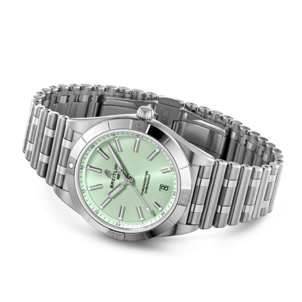 Eine silberne Armbanduhr mit Metallarmband und rundem, mintgrünem Zifferblatt. Sie verfügt über leuchtende Zeiger, Indexe und ein Datumsfenster bei 3 Uhr. Lünette und Krone der Uhr sind poliert und bilden einen Kontrast zu den gebürsteten Metallgliedern.