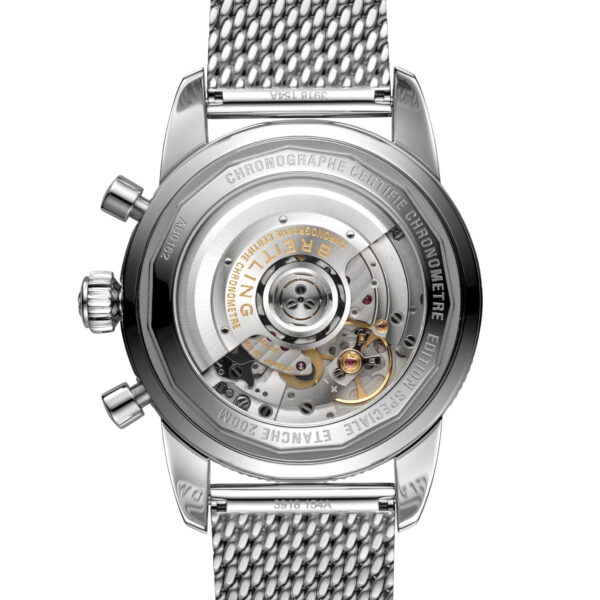 Das Bild zeigt die Rückseite einer Luxusarmbanduhr mit Metallgeflechtband. Der transparente Gehäuseboden gibt den Blick auf das komplexe mechanische Uhrwerk im Inneren frei, mit Zahnrädern und Inschriften. Das Metall ist poliert und die Chronographenknöpfe sind seitlich sichtbar.