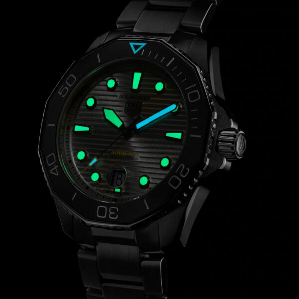 Der TAG Heuer Aquaracer Professional 300 verfügt über ein schwarzes Metallarmband mit leuchtend grünem Zifferblatt und Markierungen, auffälligen beleuchteten Zeigern und einer Datumsanzeige vor dunklem Hintergrund.