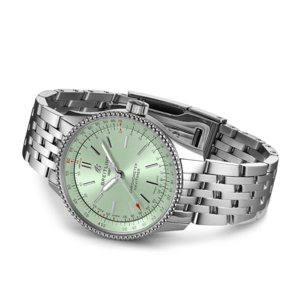 Silberne Armbanduhr mit hellgrünem Zifferblatt mit drei Zeigern und gewebtem Metallarmband. Die Lünette hat einen strukturierten Rand und das Zifferblatt enthält feine Kalibrierungsmarkierungen und Text. Der Verschluss ist in offener Position gefaltet.