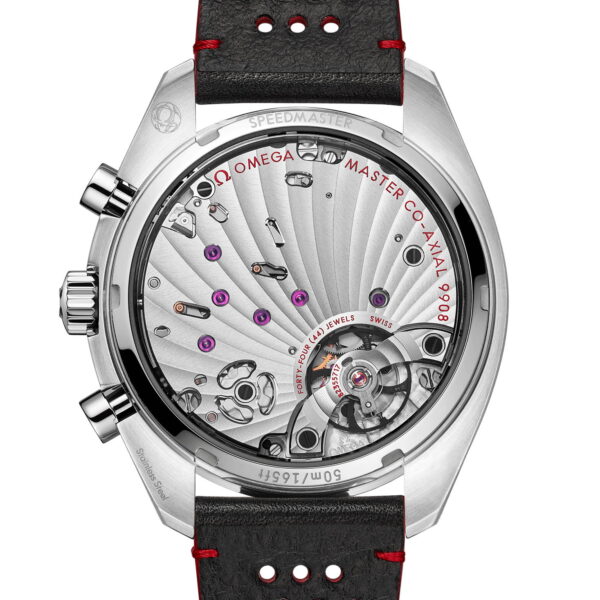 Nahaufnahme der Rückseite einer hochwertigen Uhr, die die komplexe Mechanik im Inneren mit sichtbaren roten Edelsteinen zeigt. Sie hat ein schwarzes Armband mit roten Nähten und Perforationen. Die Uhr trägt die Bezeichnung „OMEGA MASTER CO-AXIAL 9908“.