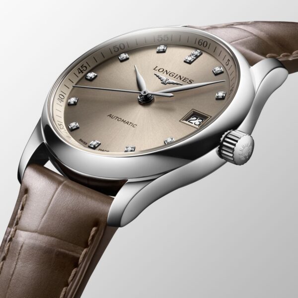 Luxuriöse Armbanduhr mit beigem Zifferblatt und Metallgehäuse, mit Diamant-Stundenmarkierungen, einer Datumsanzeige bei 3 Uhr und dem Wort „Automatic“ auf dem Zifferblatt. Die Uhr hat ein hellbraunes Lederarmband.