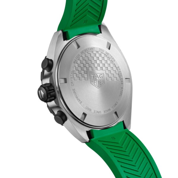 Nahaufnahme der Rückseite einer TAG Heuer-Uhr. Das silberne Gehäuse ist mit eingravierten Details und einem Schachbrettmuster versehen. Die Uhr hat ein grünes Armband und drei schwarze Knöpfe an der Seite, was auf ein Chronographenmodell hinweist.