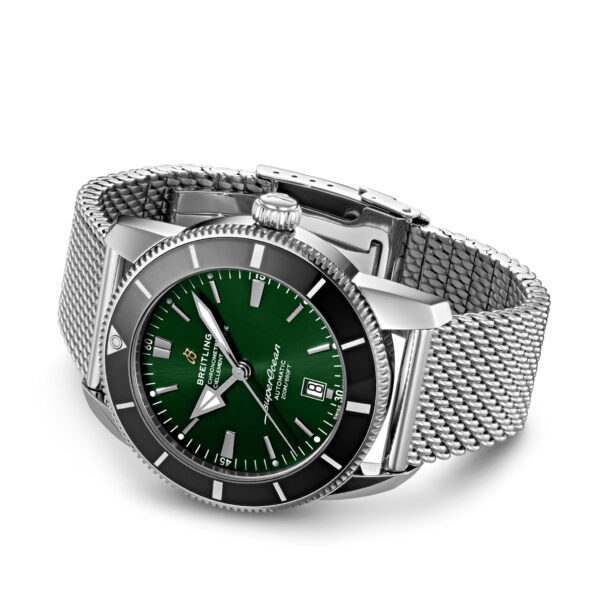 Eine Armbanduhr mit grünem Zifferblatt, silbernen Stundenmarkierungen und einem Datumsfenster. Sie hat ein elegantes Edelstahl-Mesh-Armband und ein rundes silbernes Gehäuse. Die Uhr verfügt über eine einseitig drehbare Lünette und leuchtende Zeiger und zeigt eine Mischung aus Eleganz und Funktionalität.