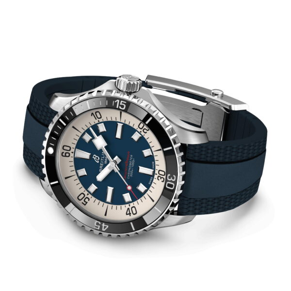 Eine luxuriöse Taucheruhr mit Edelstahlgehäuse und schwarzer drehbarer Lünette. Sie verfügt über ein dunkelblaues Zifferblatt mit weißen Stundenmarkierungen, leuchtenden Zeigern und einem Datumsfenster. Die Uhr hat ein strukturiertes blaues Gummiarmband und einen silbernen Verschluss.