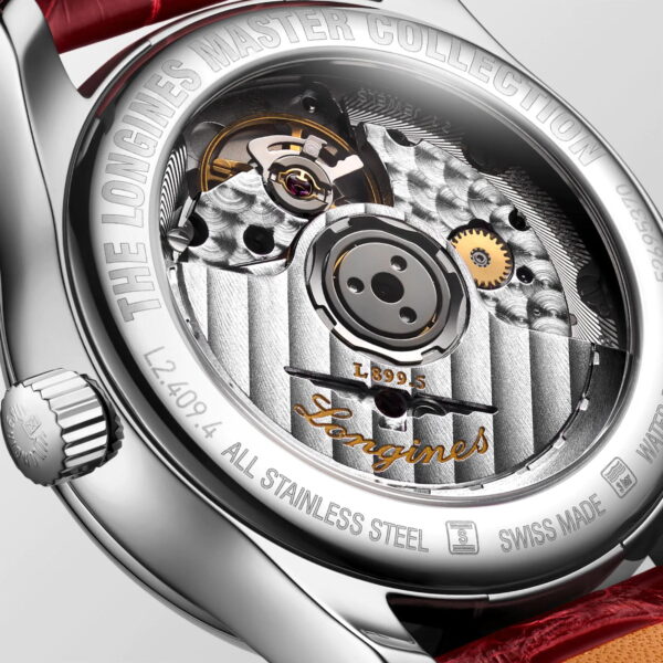 Nahaufnahme der Rückseite einer hochwertigen Armbanduhr aus Edelstahl mit freiliegendem Mechanismus. Komplexe Zahnräder und Gravuren sind sichtbar, am Rand sind „Longines Master Collection“ und andere Angaben eingraviert. Rotes Armband teilweise sichtbar.