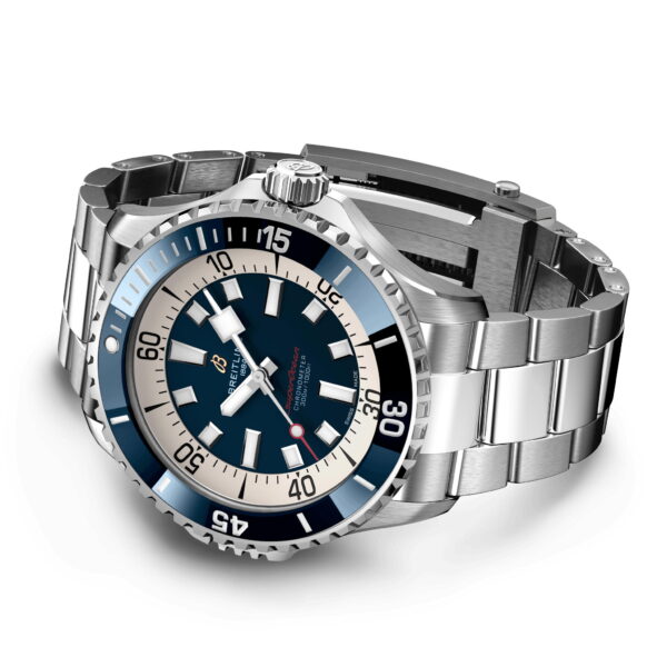 Eine Luxusarmbanduhr mit Metallarmband und marineblauer und silberner Lünette. Das Zifferblatt zeigt große weiße Stundenmarkierungen und auf der Lünette auffällige Minutenmarkierungen. Der Minutenzeiger hat eine rote Spitze und das Gehäuse ist schräg angebracht, um die seitlichen Details zu zeigen.