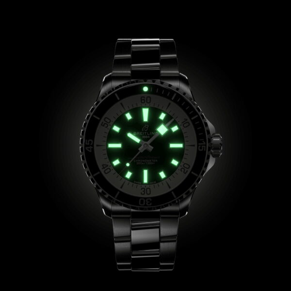 Eine schwarze Uhr mit leuchtendem Zifferblatt und Zeigern, die in dunkler Umgebung grün leuchten. Die Uhr hat ein Metallarmband und detaillierte Markierungen auf der Lünette.