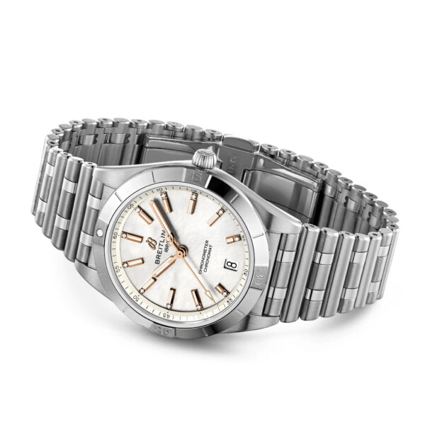 Eine silberne Armbanduhr mit Edelstahlarmband und weißem Zifferblatt mit goldfarbenen Stundenmarkierungen und Zeigern. Die Uhr verfügt über eine Datumsfunktion und den Markennamen „Breitling“ auf dem Zifferblatt. Die Zeit ist auf 10:10 eingestellt.