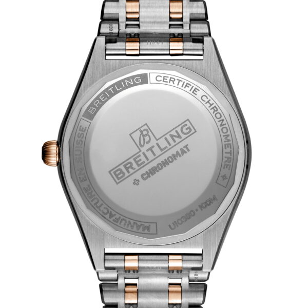 Das Bild zeigt die Rückseite einer Breitling Chronomat-Uhr. Auf der Rückseite des Gehäuses aus gebürstetem Metall sind eingravierte Texte zu sehen, darunter der Markenname und Modelldetails. Die Uhr verfügt über ein Armband aus Edelstahl und Gold.