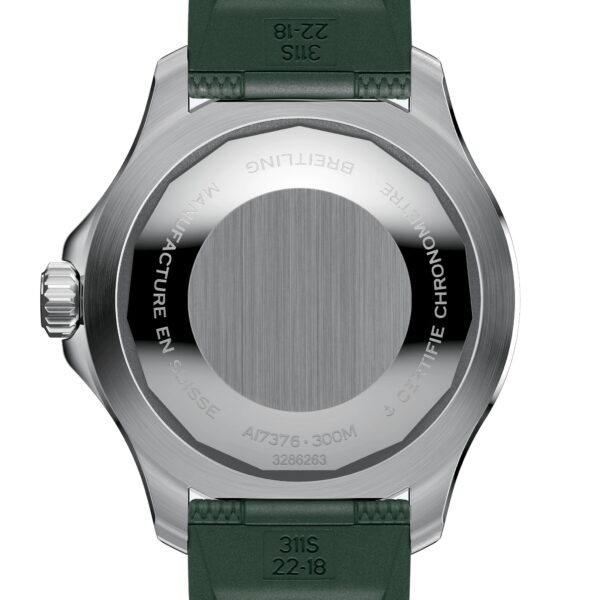 Das Bild zeigt die Edelstahlrückseite einer Armbanduhr mit Gravuren, darunter „CERTIFIE CHRONOMETRE“ und „MANUFACTURE EN SUISSE“. Die Uhr hat ein grünes Armband und eine geriffelte Krone an der Seite.