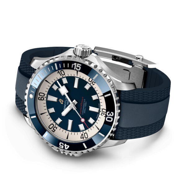 Eine luxuriöse Armbanduhr in Blau und Silber mit runder Lünette und markierten Zeitziffern. Sie hat ein blaues Zifferblatt mit silbernen Stundenmarkierungen und Zeigern, eine Datumsanzeige bei 3 Uhr und ein strukturiertes blaues Armband mit Metallverschluss.