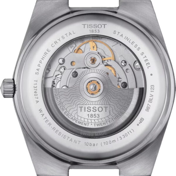 Rückseite einer Tissot-Uhr mit mechanischem Uhrwerk. Das silberne Gehäuse umgibt sichtbare Zahnräder und komplizierte Komponenten. Text rund um das Gehäuse weist auf Merkmale wie Saphirglas, Edelstahl und Wasserdichtigkeit bis 100 m hin.