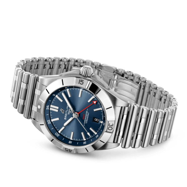 Die Breitling Chronomat Automatic GMT 40 ist eine Luxusuhr mit silbernem Metallarmband, blauem Zifferblatt, silbernen Zeigern, weißen Markierungen und einer Datumsanzeige bei 3 Uhr. Sie verfügt über eine drehbare Lünette und das Markenlogo unterhalb der 12-Uhr-Position.