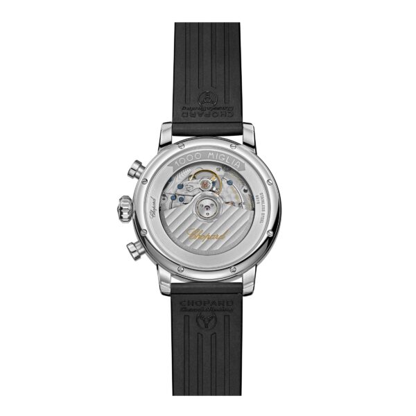 Rückansicht der Chopard Mille Miglia Classic Chronographenuhr mit schwarzem Gummiarmband. Das transparente Gehäuse offenbart komplizierte Mechanik, sichtbare Zahnräder und die „Chopard“-Gravur. Auf dem Rand sind „1000 Miglia“ und ein kariertes Flaggenmuster zu sehen.