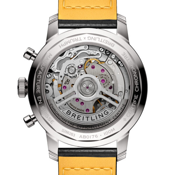 Eine Nahaufnahme der Breitling TopTime B01 41 Triumph-Uhr offenbart ihr freiliegendes mechanisches Uhrwerk und zeigt komplizierte Zahnräder und Komponenten durch einen transparenten Gehäuseboden. Die Uhr verfügt über ein gelbes Armband und ein Metallgehäuse mit eingraviertem Text.
