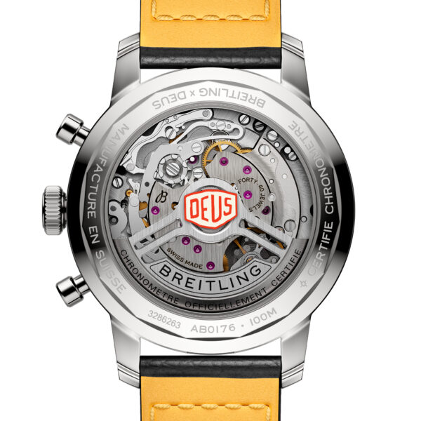 Die Breitling TopTime B01 41 Deus-Uhr zeigt eine Nahaufnahme der Rückseite, die das komplizierte mechanische Uhrwerk durch ein transparentes Gehäuse zeigt. Die Markennamen „Breitling“ und „Deus“ sind als eingravierter Text entlang des Rands sichtbar und die Uhr hat ein gelbes Lederarmband.