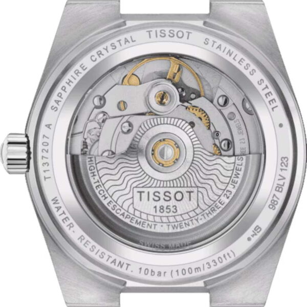 Die Rückseite des Tissot PRX Powermatic 80 35MM ist in Nahaufnahme dargestellt. Das mechanische Uhrwerk im Inneren ist durch eine transparente Abdeckung zu sehen und zeigt Zahnräder und Unruh. Die Gravuren lauten „Saphirglas“, „Edelstahl“, „High-Tech-Hemmung“ und „23 Steine“.