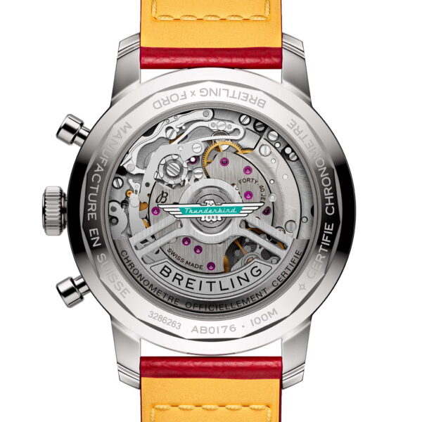 Das Bild zeigt die Rückseite einer Breitling Top Time B01 Ford Thunderbird-Armbanduhr mit einem transparenten Gehäuse, das das komplizierte mechanische Uhrwerk offenbart. „Thunderbird“ und andere Markierungen sind auf dem äußeren Rand eingraviert. Das Armband ist in Gelb und Rot gehalten.