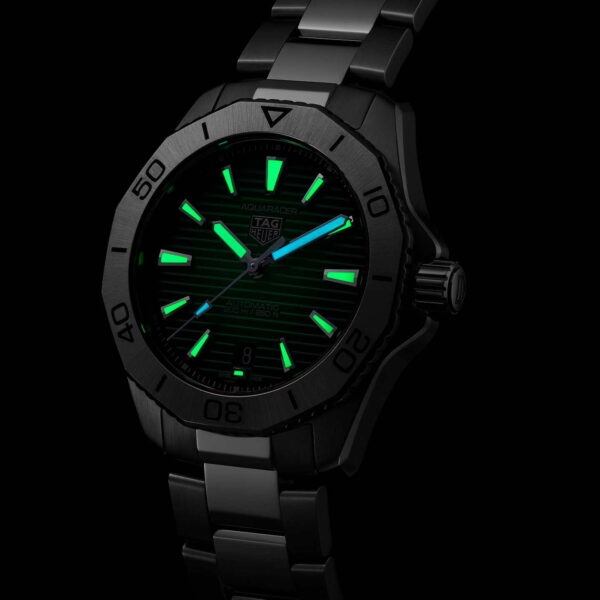 Die Armbanduhr TAG Heuer Aquaracer Professional 200 verfügt über ein dunkles Metallarmband, ein schwarzes Zifferblatt mit leuchtend grünen Stundenmarkierungen und Zeigern, ein Logo unterhalb der 12-Uhr-Position und ein Datumsfenster bei der 6-Uhr-Position.