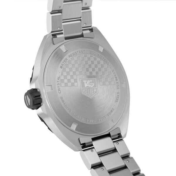 Das Bild zeigt die Rückseite einer Armbanduhr aus Edelstahl mit eingravierten Details, darunter das TAG Heuer-Logo und ein kariertes Muster. Die Uhr hat ein Metallarmband und eine schwarze Krone an der Seite.