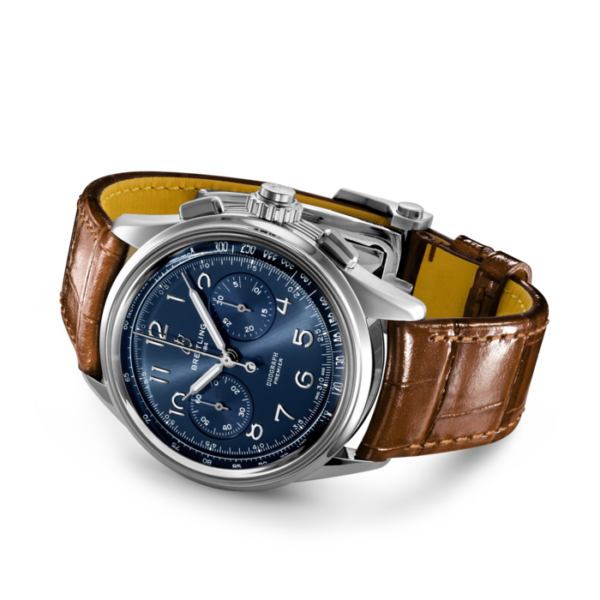 Die Breitling Premier B15 Duograph 42 ist eine Luxusuhr mit blauem Zifferblatt mit drei Hilfszifferblättern, silbernen Stundenmarkierungen und Zeigern. Sie hat ein Edelstahlgehäuse und ein braunes Lederarmband mit Krokodilmuster. An der Seite befinden sich eine Krone und Drücker für die Funktionalität.