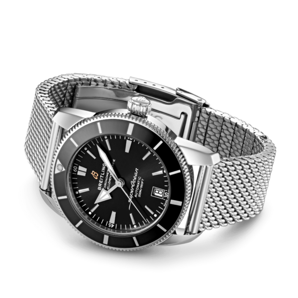 Die Breitling Superocean Heritage B20 42 verfügt über ein silbernes Mesh-Armband, ein schwarzes Zifferblatt mit silbernen Stundenmarkierungen, eine Datumsanzeige bei 3 Uhr, den „Superocean“-Schriftzug auf dem Zifferblatt und eine schwarze Lünette mit poliertem Metallrand.