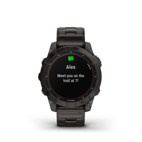 Die Garmin Fenix 7 Sapphire Solar ist eine schwarze Smartwatch mit robustem Design, einem Metallarmband und rundem Zifferblatt mit einer Nachricht von „Alex“: „Wir treffen uns um 7 auf dem Weg!“.