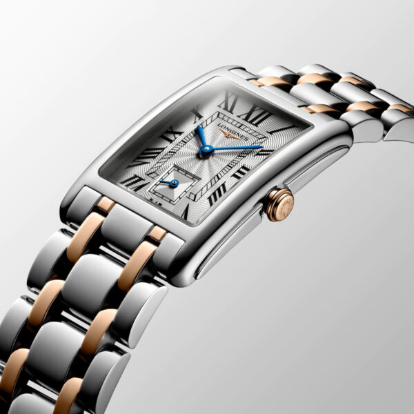 Die Longines Dolce Vita ist eine Luxusuhr mit einem rechteckigen Armband aus Edelstahl in Silber und Roségold, römischen Ziffern, blauen Zeigern, einem Hilfszifferblatt für die kleine Sekunde, einem strukturierten Zifferblatt und einer Krone aus Roségold.