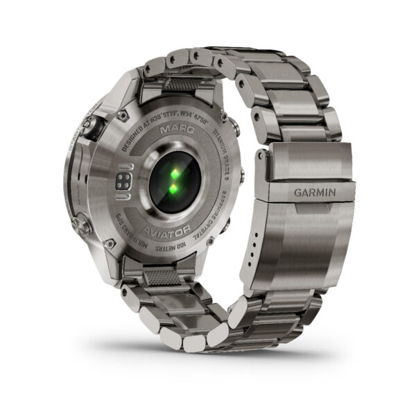 Die silberne Smartwatch Garmin Marq Aviator 2.Gen mit Metallarmband verfügt über ein leuchtendes grünes Licht auf der Rückseite sowie eingravierte Details und sichtbares „Aviator“-Branding.