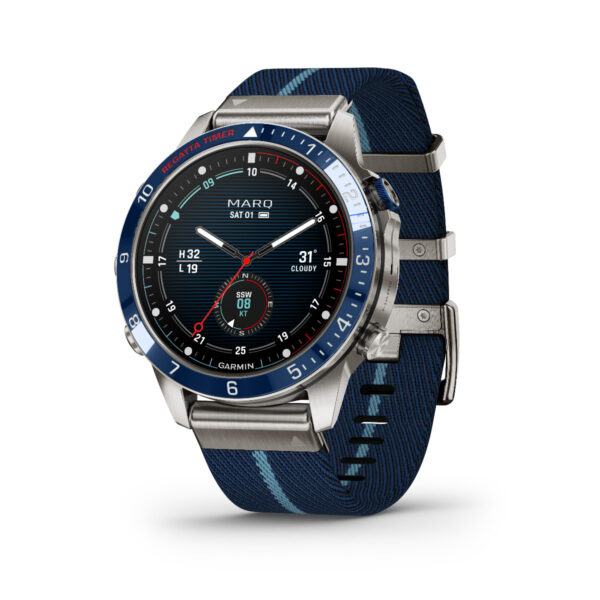 Die Garmin Marq Captain 2.Gen ist eine moderne Smartwatch mit einem blau-silbernen Metallgehäuse und einem blauen Stoffarmband. Das Zifferblatt zeigt mehrere Zifferblätter, die Informationen wie Datum, Temperatur und Höhe anzeigen.