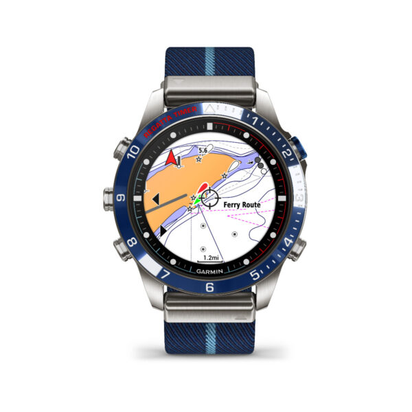 Die Smartwatch Garmin Marq Captain 2.Gen. verfügt über eine Seekarte auf ihrem Bildschirm, ein blau-schwarzes Zifferblatt mit Zahlen, drei Knöpfe auf jeder Seite und ein Stoffarmband mit blauen Streifen. Die Karte zeigt eine Fährroute und Navigationssymbole.