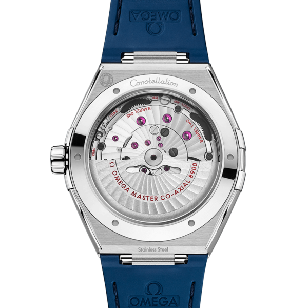 Das Bild zeigt die Rückansicht einer OMEGA Constellation-Uhr mit einem blauen Armband mit Omega-Logo und zeigt komplizierte Zahnräder und Mechanismen mit der Aufschrift „Omega Master Co-Axial 8900“ und „Edelstahl“.