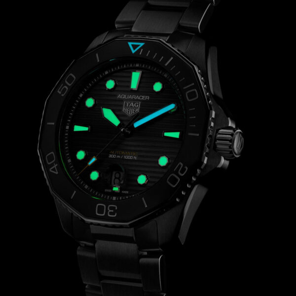 Die TAG Heuer Aquaracer Professional 300 ist eine schwarze Taucheruhr mit grün leuchtenden Stundenmarkierungen und Zeigern, einer drehbaren Lünette und den Anzeigen „Aquaracer“ und „Tag Heuer“. Ihr robustes schwarzes Metallband sorgt für Langlebigkeit, während Stunden und Minuten auch bei schwachem Licht sichtbar bleiben.