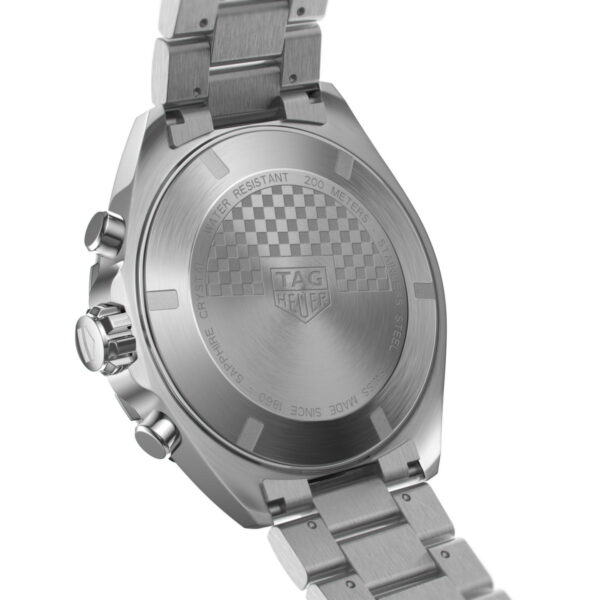 Das Bild zeigt die Rückseite der TAG Heuer Formula 1-Uhr mit Metallarmband, Schachbrettmuster und Gravuren, die auf eine Wasserdichtigkeit bis 200 Meter hinweisen. Es ist aus einem Winkel betrachtet, sodass die seitlichen Knöpfe und die Krone sichtbar sind.
