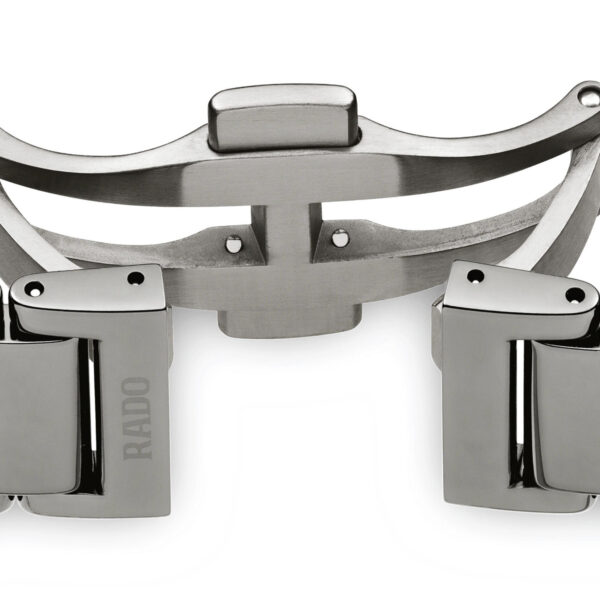 Eine Nahaufnahme zeigt den offenen Verschluss des silbernen Metallbands der Rado True Automatic Open Heart und hebt dessen Scharniere und Schließmechanismus hervor. Die rechteckigen Glieder haben eine glatte, glänzende Oberfläche, auf einem ist „RADO“ eingraviert.