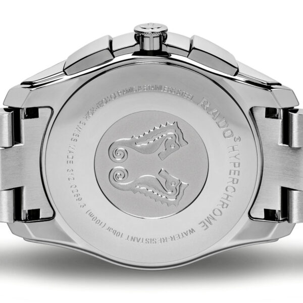Nahaufnahme der Rückseite einer silbernen Uhr mit zwei eingravierten Seepferdchen in der Mitte und umgebenden Wörtern und Zahlen, darunter „RADO“ und „HYPERCHROME“. Dieser Rado Hyperchrome Chronograph XXL hat ein Metallgliederarmband.
