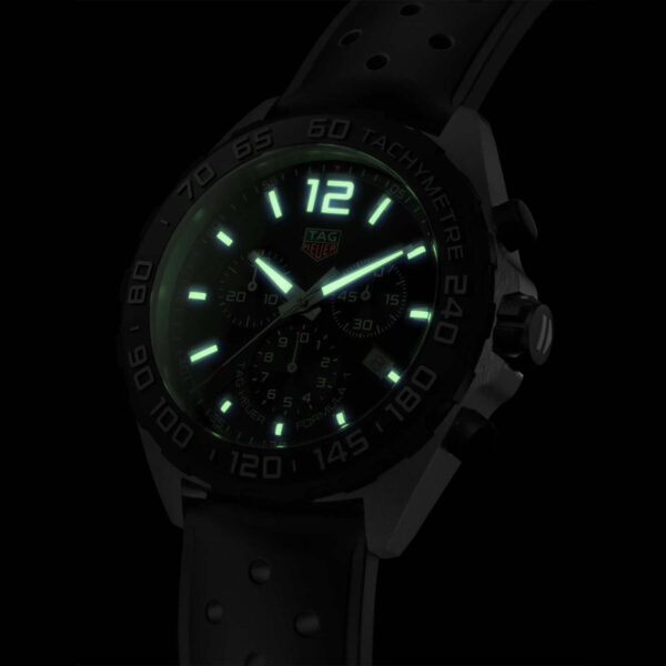 Die Tag Heuer Formula 1 ist eine schwarze Sportuhr mit Tachymeterskala und leuchtend grünen Zeigern und Markierungen auf dem Zifferblatt. Oben befindet sich eine markante „12“ und das schwarze Armband mit kreisförmigen Perforationen leuchtet im Dunkeln.