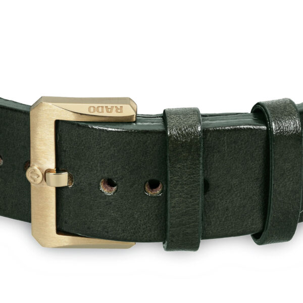 Das Rado Captain Cook Automatic Bronze-Uhrenarmband besteht aus dunkelgrünem Leder mit glänzender Oberfläche und verfügt über eine goldene Schnalle mit eingraviertem Markennamen. Es verfügt über mehrere Einstelllöcher und eine befestigte Schlaufe zum Sichern des Bandendes.