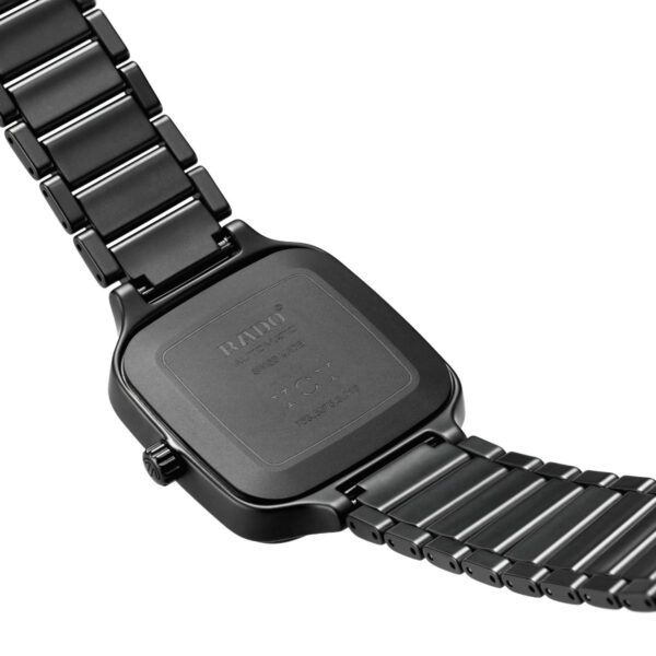 Die Rado True Square Unidigital zeigt die Rückseite einer schwarzen Metallarmbanduhr mit quadratischem Gehäuse und Gliederarmband. Eingravierter Text ziert die Rückseite, während die seitliche Krone Anpassungen ermöglicht. Die polierten Glieder reflektieren das Licht elegant.