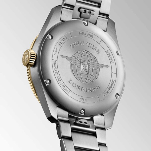 Das Bild zeigt die Rückseite einer Longines Spirit Zulu Time-Armbanduhr aus Edelstahl mit einem eingravierten Globus- und Pfeildesign. „Zulu Time“ und „Longines“ sind eingraviert. Die Uhr hat ein Metallarmband und eine goldfarbene Krone.