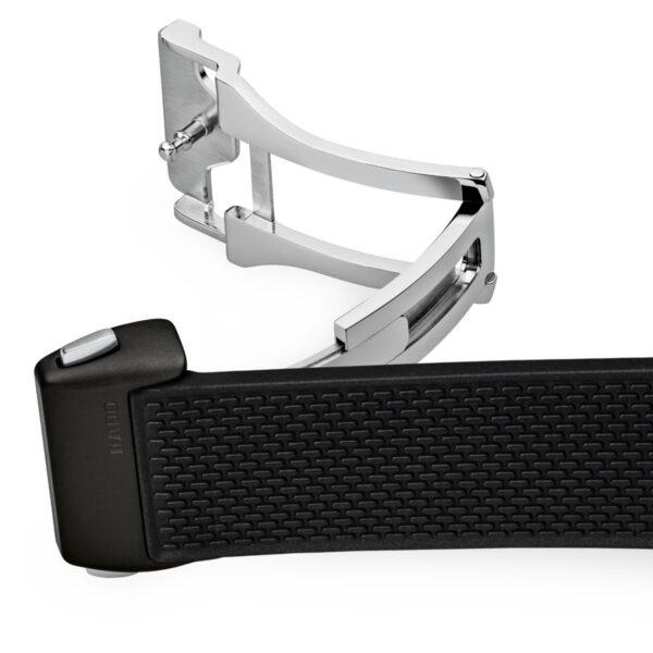 Eine Nahaufnahme der Metallschließe der Captain Cook High-Tech Ceramic, die an ihrem strukturierten schwarzen Gummiarmband befestigt ist. Die teilweise geöffnete und abgewinkelte Schließe zeigt ihr elegantes Design und ihren Mechanismus.