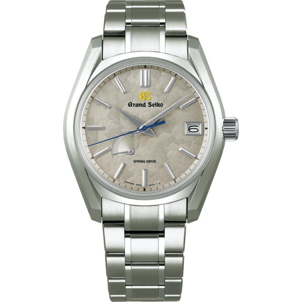 Die Grand Seiko Heritage Taisetsu SBGA415G Uhr besticht durch ein silbernes Metallarmband, ein strukturiertes cremefarbenes Zifferblatt mit silbernen Stundenmarkierungen und Zeigern, einen blauen Sekundenzeiger und ein Datumsfenster bei 3 Uhr. „Grand Seiko“ und „Spring Drive“ sind deutlich sichtbar.