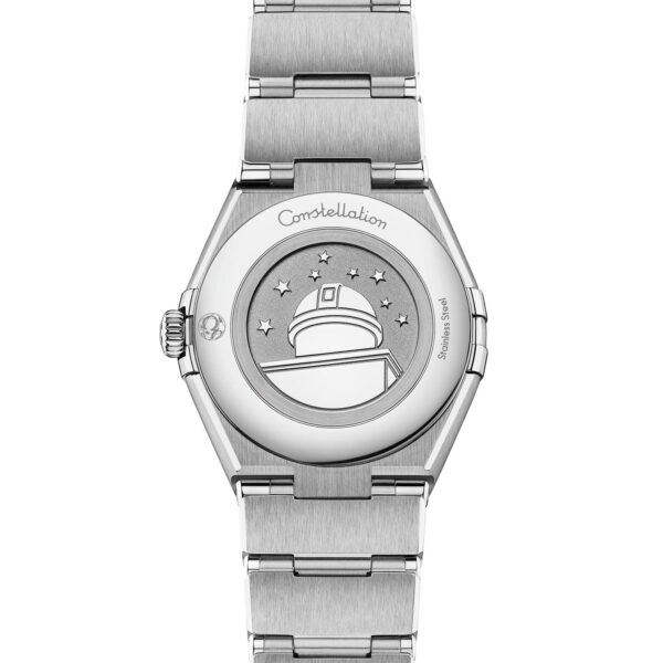 Rückansicht der OMEGA Constellation Manhattan, einer Luxusarmbanduhr mit Edelstahlarmband. Der Gehäuseboden ist mit einem eingravierten Observatorium, umgeben von Sternen, und dem Schriftzug „Constellation“ verziert.