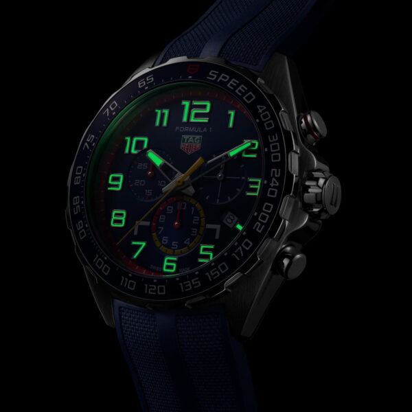 Die TAG Heuer Formula 1 X Red Bull Racing Uhr besticht durch ein detailreiches Zifferblatt mit leuchtend grünen Markierungen, Hilfszifferblättern und einem blauen Armband. Die Lünette zeigt Geschwindigkeitsmessungen an, ergänzt durch silberne Chronographendrücker und eine markante Krone – alles in einem dunklen und stimmungsvollen Ambiente.