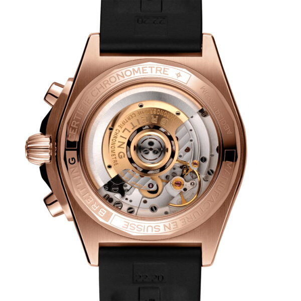Das Bild zeigt die Rückseite einer Breitling Chronomat B01 42 mit transparentem Gehäuse, das den Blick auf das komplexe mechanische Uhrwerk freigibt. Das Gehäuse ist goldfarben, das Armband ist schwarz und die Gravuren zeigen Zertifizierung und Herkunft.